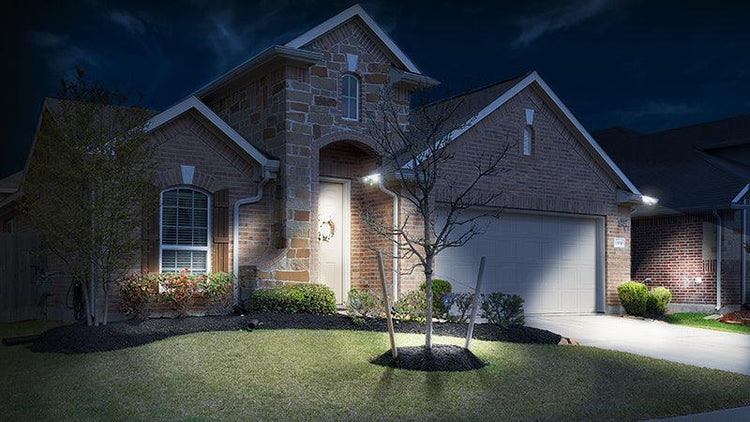 Brick home lit up at night a couple EZ Solar Gutter Light by STKR