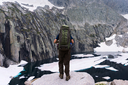 person wearing a bug-out bag in a winter mountainous setting