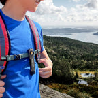 LP-EDC+ 8.0 Low Profile Everyday Carry Ultra-Thin Spot & Flood Flashlight clipped onto a backpack strap of a male hiker on a mountain area over looking beautiful scenery