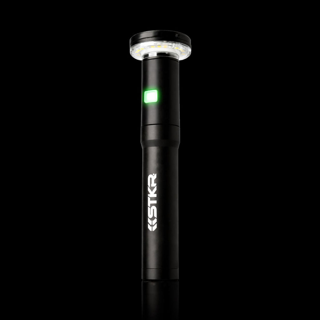 Black handheld light with green light on a black background