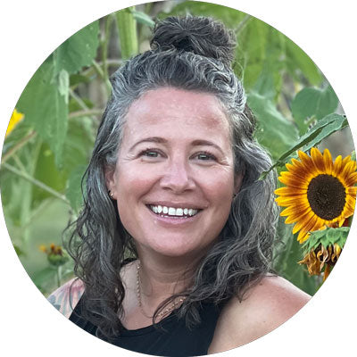 Bio picture of Cammy smiling in front of sunflowers