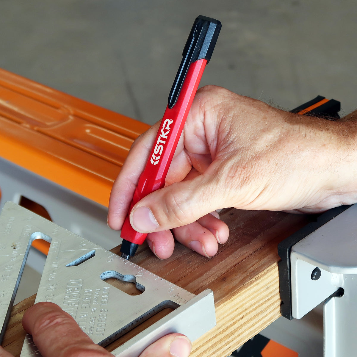 Marking a 2x4 on sawhorses with the STKR Mechanical Carpenter Pencil and a speed square
