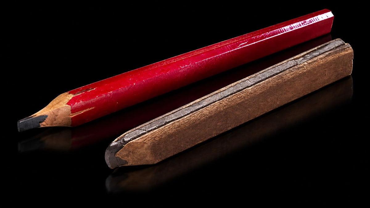 A new wooden carpenter pencil next to a worn, whittled-down one on black